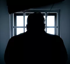 man in prison behind bars